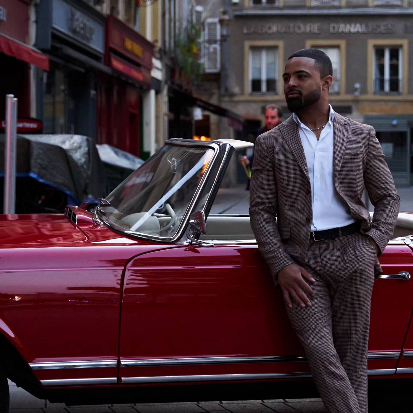 Homme élégant devant une voiture rouge
